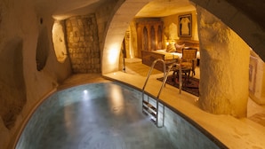 A spa area with a pool, a massage chair, and a massage table. - Kayakapi Premium Caves - Cappadocia (Ürgüp)