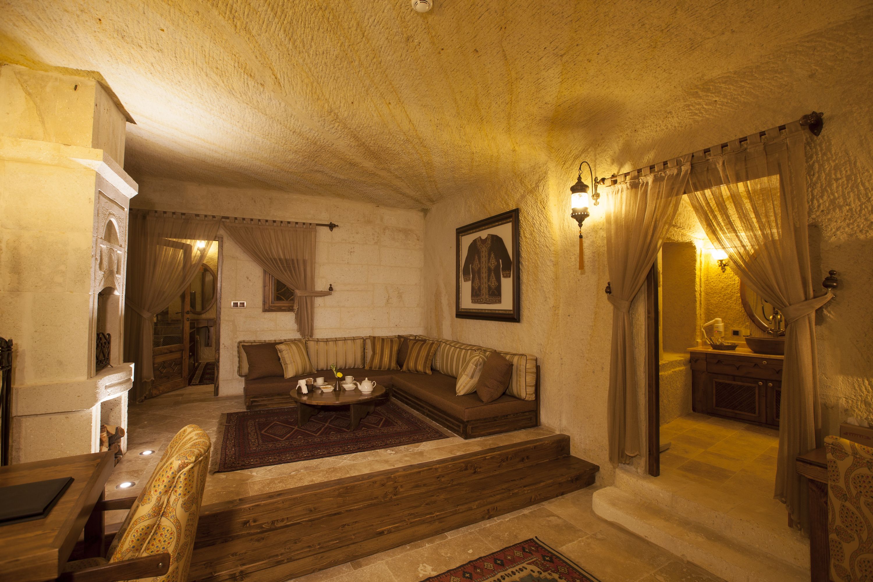 A cozy living room with a sofa, a coffee table, and a fireplace. There is a staircase leading to another room.
