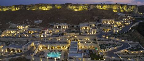 Un resort bien iluminado con varias edificaciones, una piscina y un camino sinuoso.