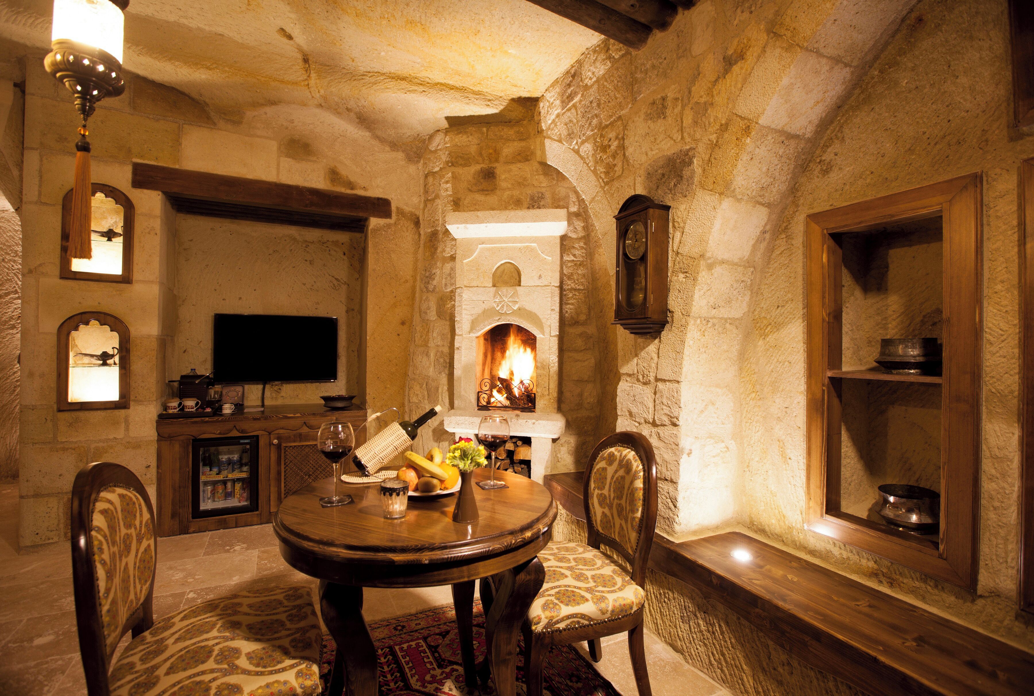 Habitación con paredes de piedra, chimenea, muebles de madera y televisor.
