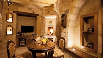 Habitación con paredes de piedra, chimenea, muebles de madera y televisor.