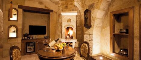 A stone-walled room with a fireplace, wooden furniture, and a television.