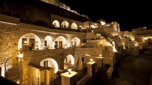 A historic stone building with multiple arches and balconies, illuminated by warm lighting. - Kayakapi Premium Caves - Cappadocia (Ürgüp)