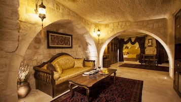 Ein gemütliches Zimmer mit einer Steinwand, einem hölzernen Sofa, einem Tisch und einem gemusterten Teppich.