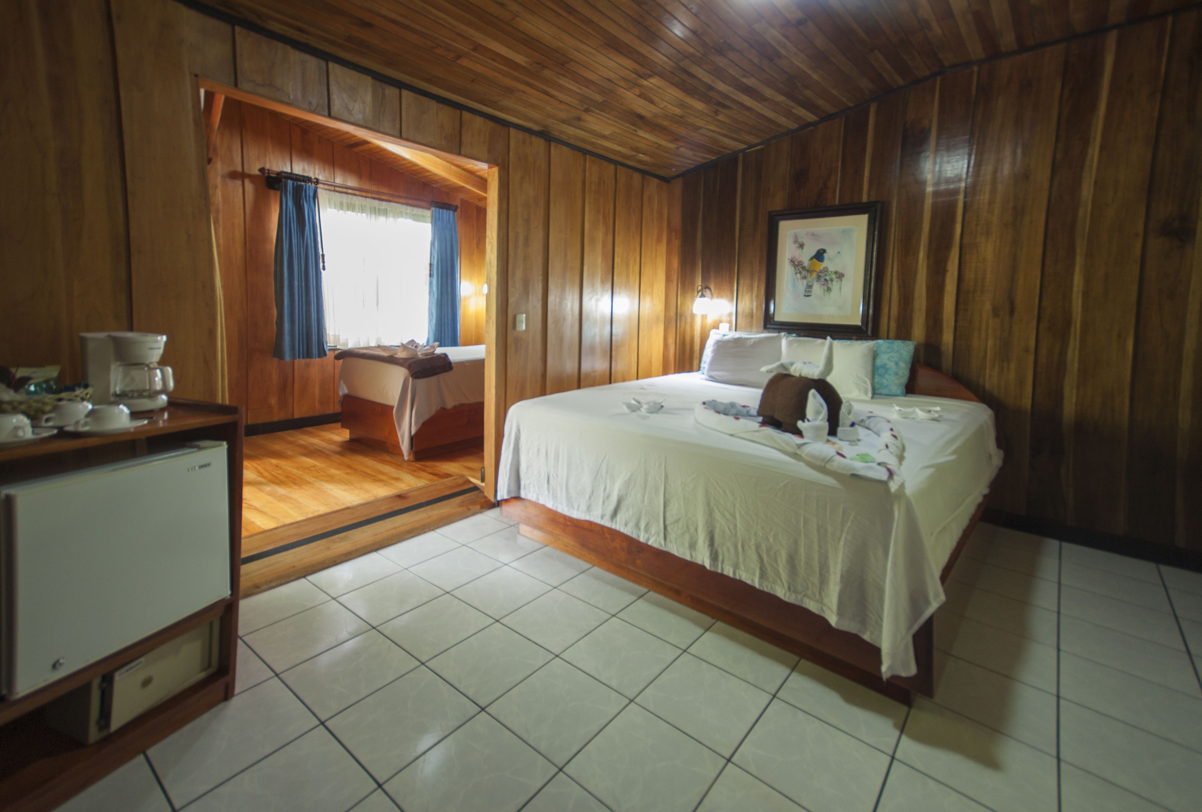 A wooden-paneled room with a bed, a desk, and a window with curtains.