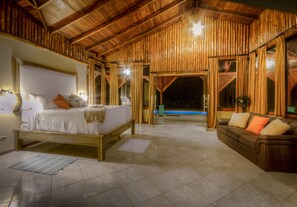 Um quarto espaçoso com uma cama grande, um sofá e vista para uma piscina.