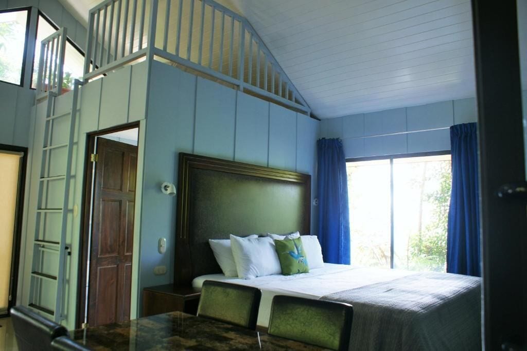 Ein Schlafzimmer mit einem Bett, einem Schreibtisch und einem Fenster mit Vorhängen.