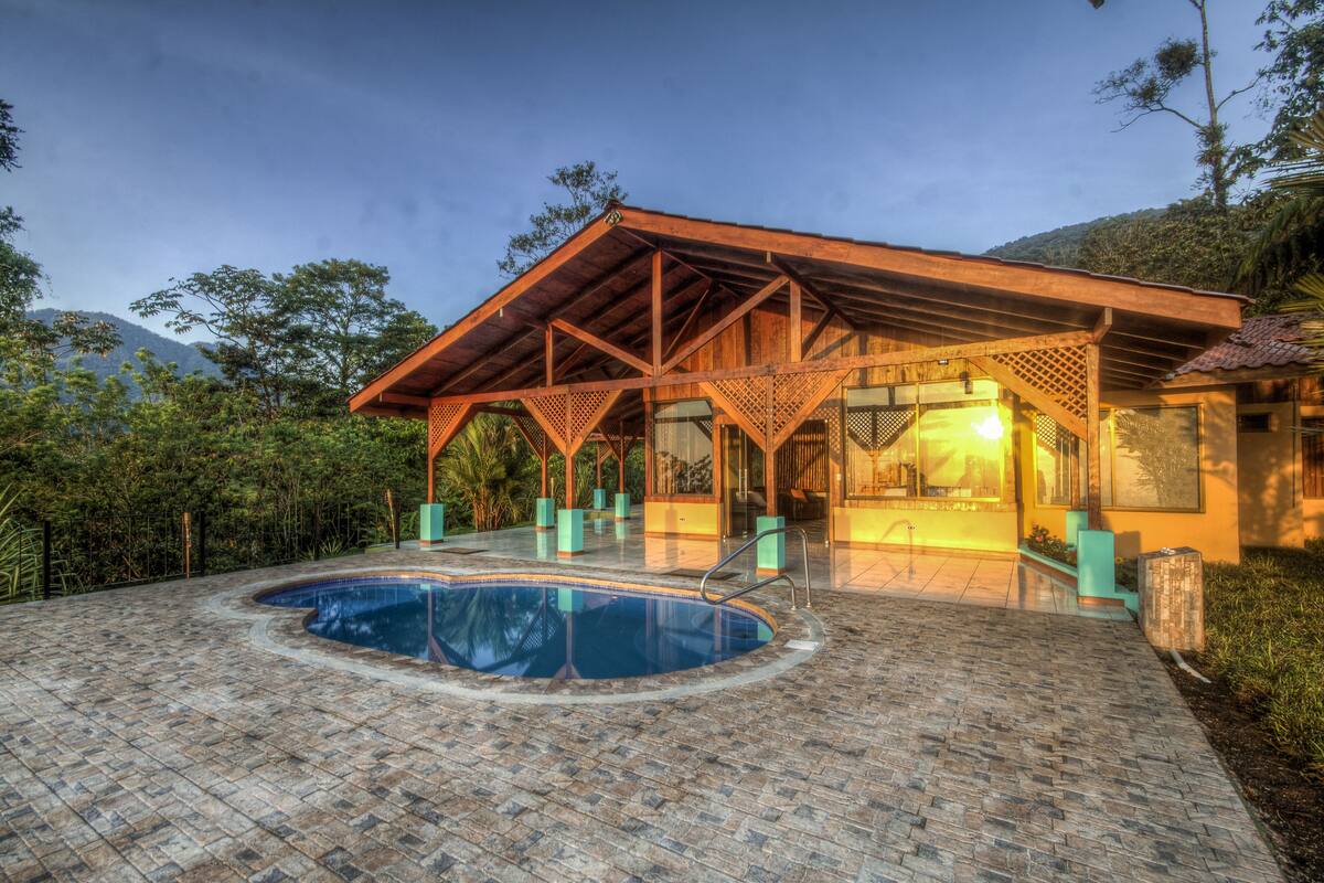 A pool area with a wooden pergola and a hot tub.