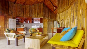 A bamboo-themed interior with a wooden sofa, a dining table, and a kitchen area. - Arenal Waterfall Lodge (La Fortuna)