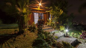 A well-lit outdoor area with a wooden structure, surrounded by various plants and a gravel pathway leading to it. - Arenal Waterfall Lodge (La Fortuna)
