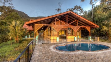 Zona de piscina con un espacio de descanso cubierto y una piscina.