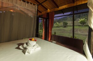 Un dormitorio con una cama grande, vistas al exterior y una ventana con cortinas.