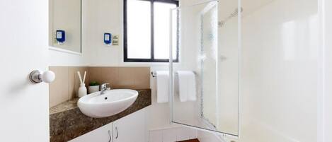 Une salle de bain moderne avec un lavabo blanc, une douche en verre et un plancher en bois.
