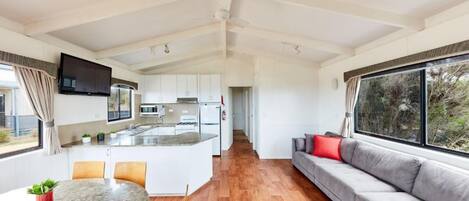 A modern kitchen with white cabinets, a central island, and a dining area with a table and chairs.