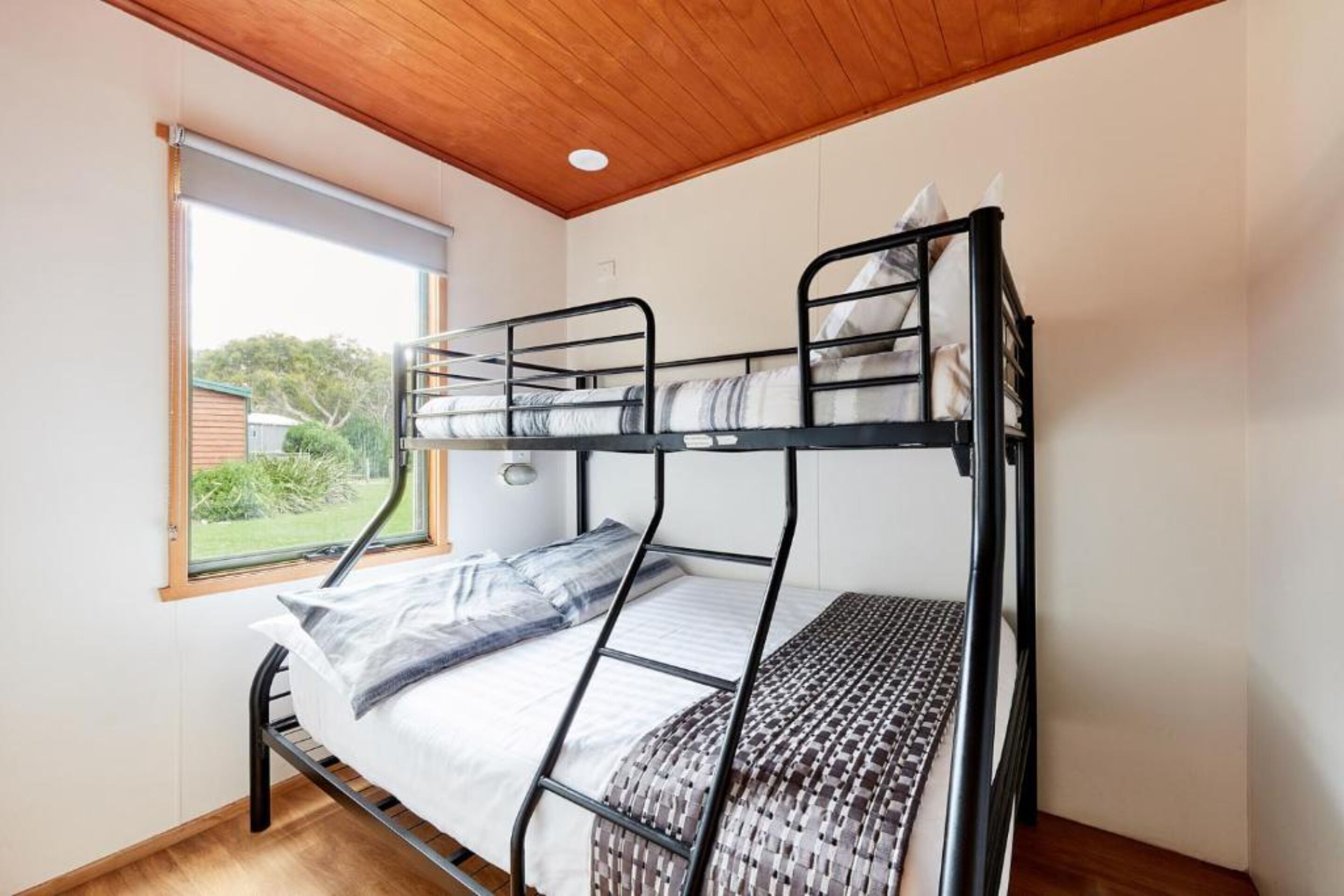 Un lit superposé avec un plafond en bois et une fenêtre donnant sur un paysage verdoyant.