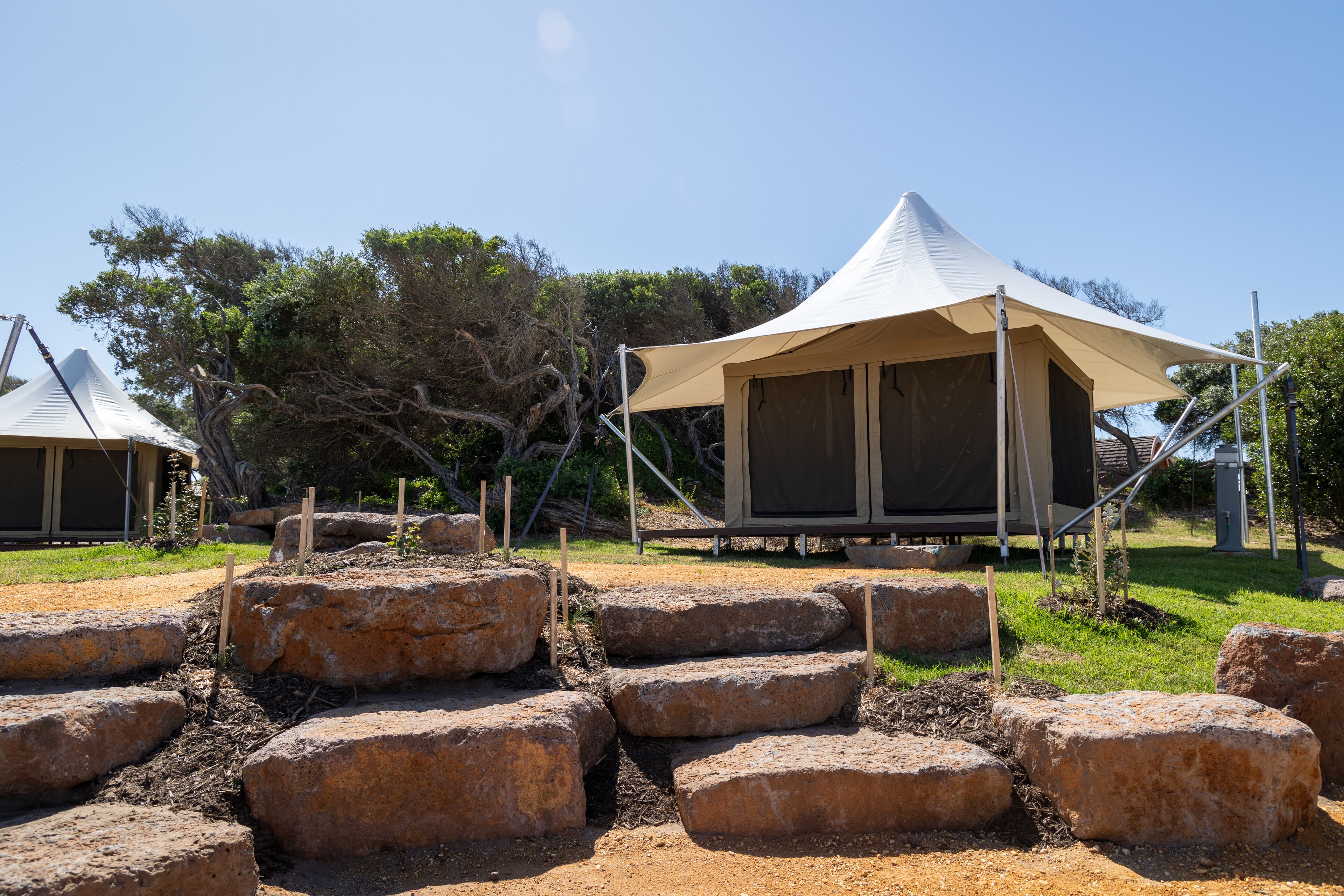 Un terrain de camping avec des tentes et de gros rochers disposés selon un motif particulier.