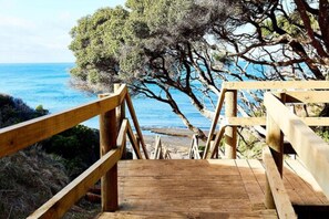 A wooden staircase leading to a beach with a view of the sea and trees. - Torquay Foreshore Caravan Park (Torquay)
