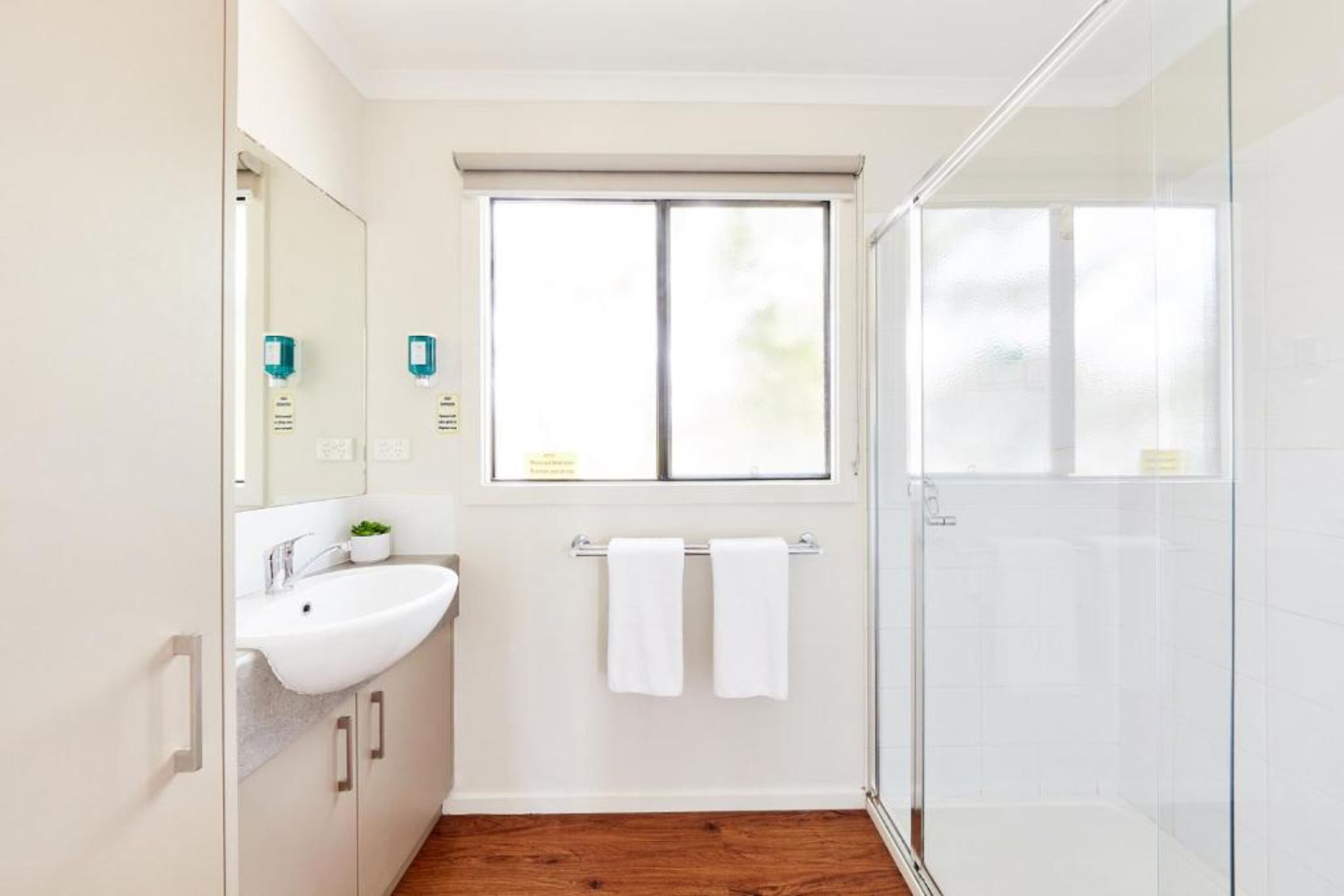 Une salle de bain moderne avec un lavabo blanc, un miroir et une fenêtre.