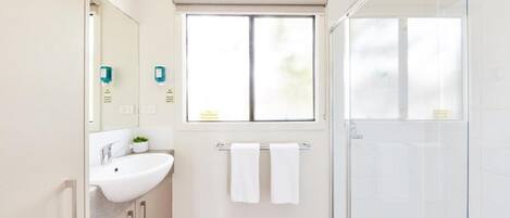 Une salle de bain moderne avec un lavabo blanc, un miroir et une fenêtre.