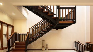 Un escalier moderne avec des marches en bois et des rampes noires, menant à l’étage supérieur.