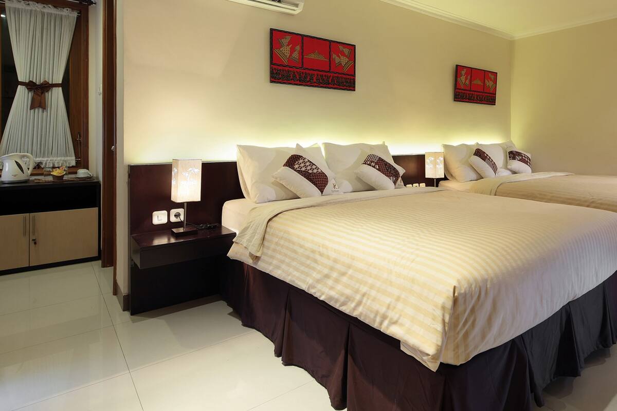 Une chambre d’hôtel avec deux lits, une table de chevet, une lampe, une fenêtre avec des rideaux et des œuvres d’art murales.