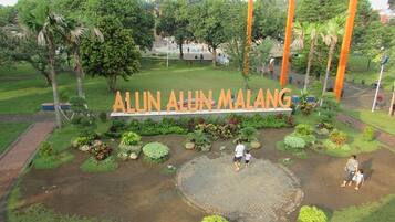 A landscaped area with a sign reading "ALUN ALUN MALANG" surrounded by greenery and pathways.