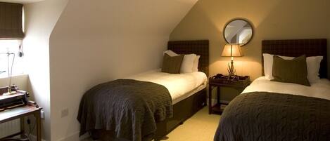 A room with two beds, a desk, and a lamp.