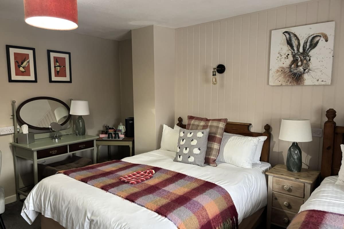 A hotel room with a bed, bedside tables, a desk, a mirror, and artwork on the walls.
