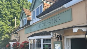 Un bâtiment sur lequel on peut lire l’inscription : « The Three Cups Inn ».