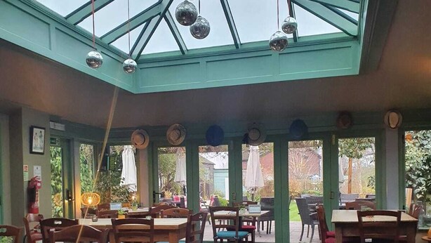 Un restaurant doté d’un plafond en verre, de tables et de chaises en bois, et offrant une vue sur l’extérieur.