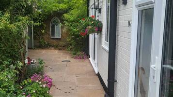 A narrow stone pathway leading to a white building with large windows and a brick chimney.