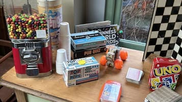 Una mesa con juegos de mesa, una máquina de dulces y una ventana con vistas a árboles.