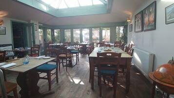 A restaurant with wooden tables and chairs, a skylight, and framed artwork on the walls.