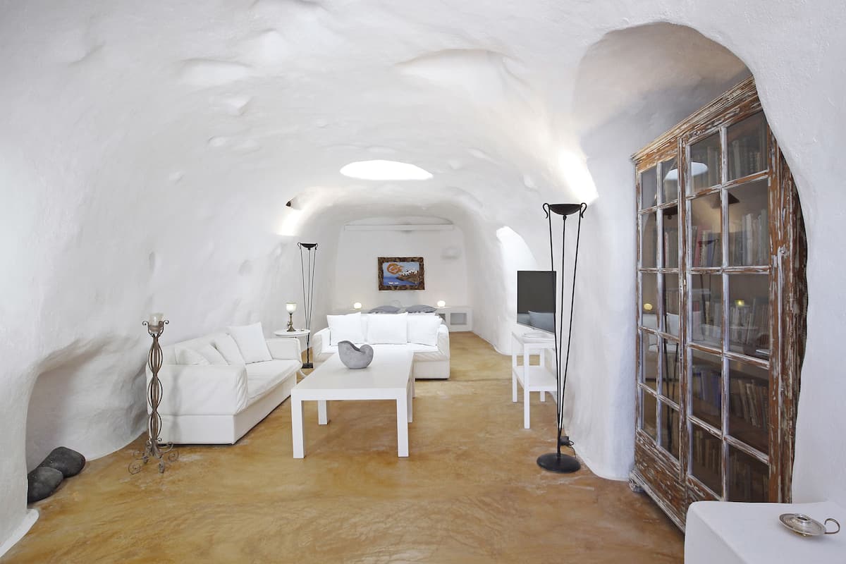 A cozy, white-themed interior with a sofa, coffee table, and a bookshelf.