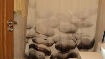 A bathroom with a shower curtain featuring a bear print, a toilet, and a wooden door.