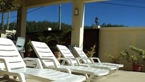 A row of white lounge chairs under a covered area with a view of the sea. - Monalysa St Honoré Apartment & Studio (Grand-Baie)