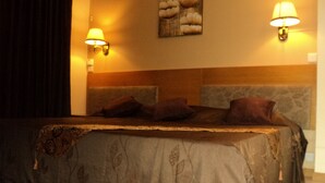 A hotel room with a large bed, two wall-mounted lamps, and a decorative headboard. - Monalysa St Honoré Apartment & Studio (Grand-Baie)