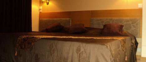 A hotel room with a large bed, two wall-mounted lamps, and a decorative headboard.
