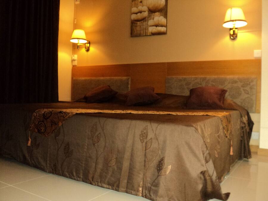 Una habitación de hotel con una cama grande, dos lámparas de pared y un cabecero decorativo.