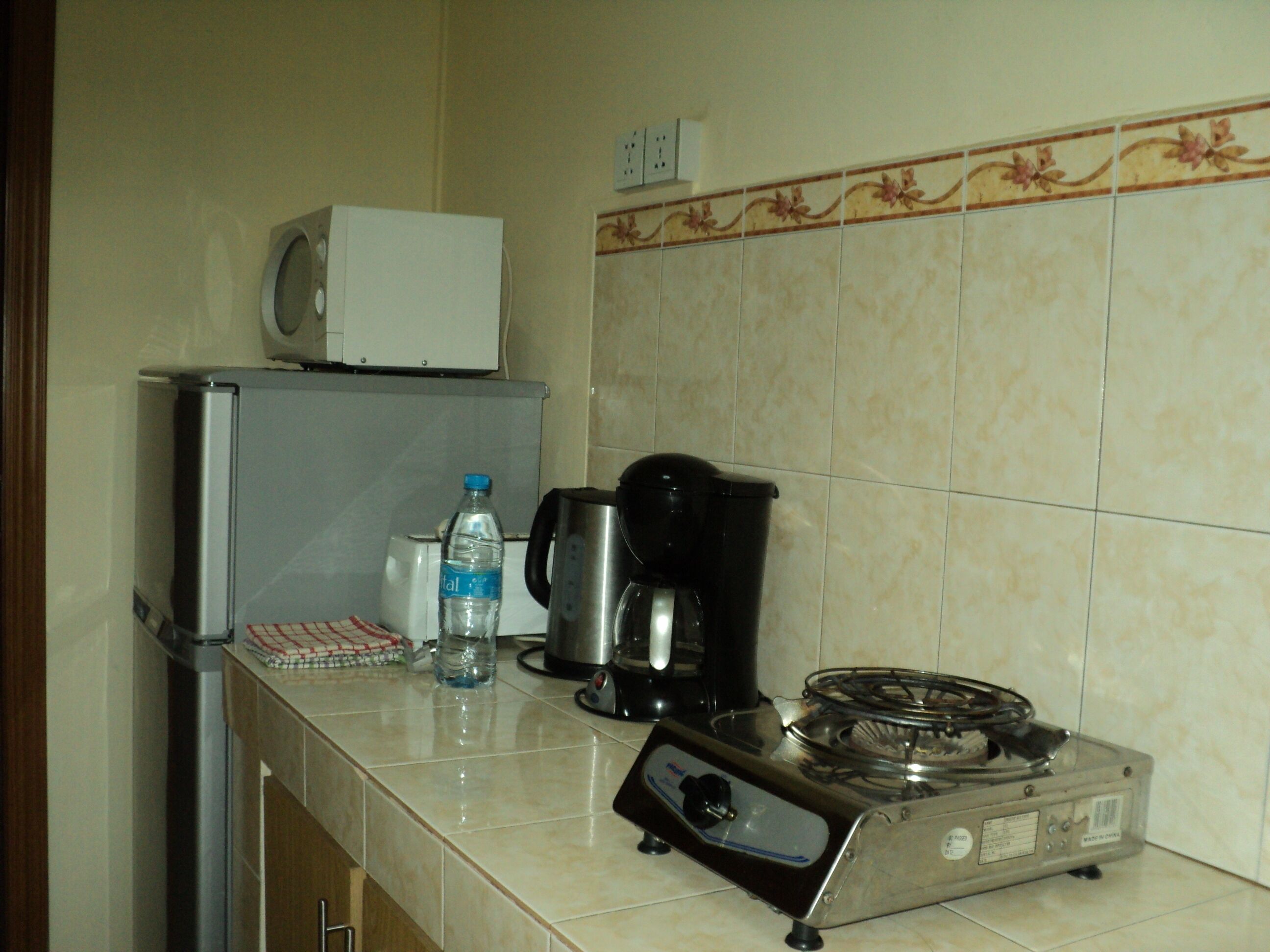 Una cucina con frigorifero, una bottiglia d'acqua, una macchina da caffè e un piano cottura a gas.