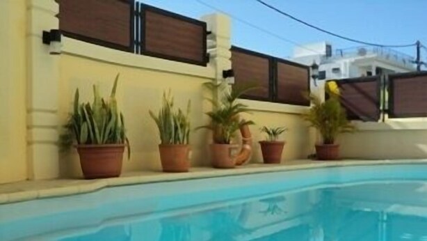A swimming pool with potted plants along the edge. - Monalysa St Honoré Apartment & Studio (Grand-Baie)