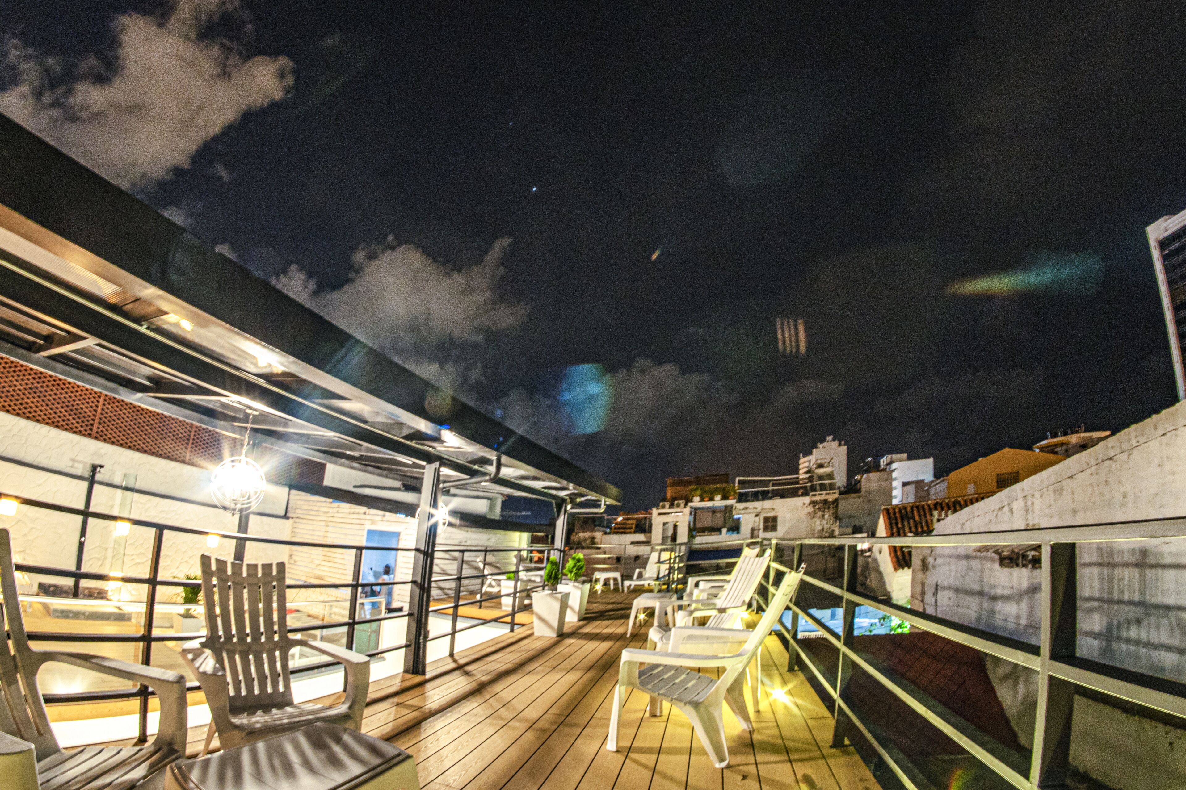 A rooftop terrace with outdoor seating and a view of the city skyline at night.
