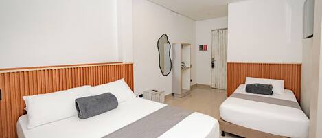 Ein Hotelzimmer mit zwei Betten, einem Holz-Kopfteil, einem Nachttisch, einem Spiegel und einer Tür zu einem Badezimmer.