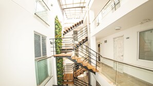 Een meerlaags interieur met een spiltrap, glazen balustrades en een groene verticale tuin.