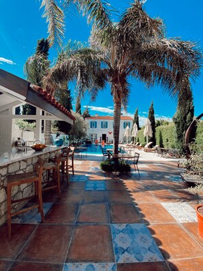 A poolside area with a stone bar, wooden chairs, and a tiled patio. - BeyEvi Alacati (Cesme)