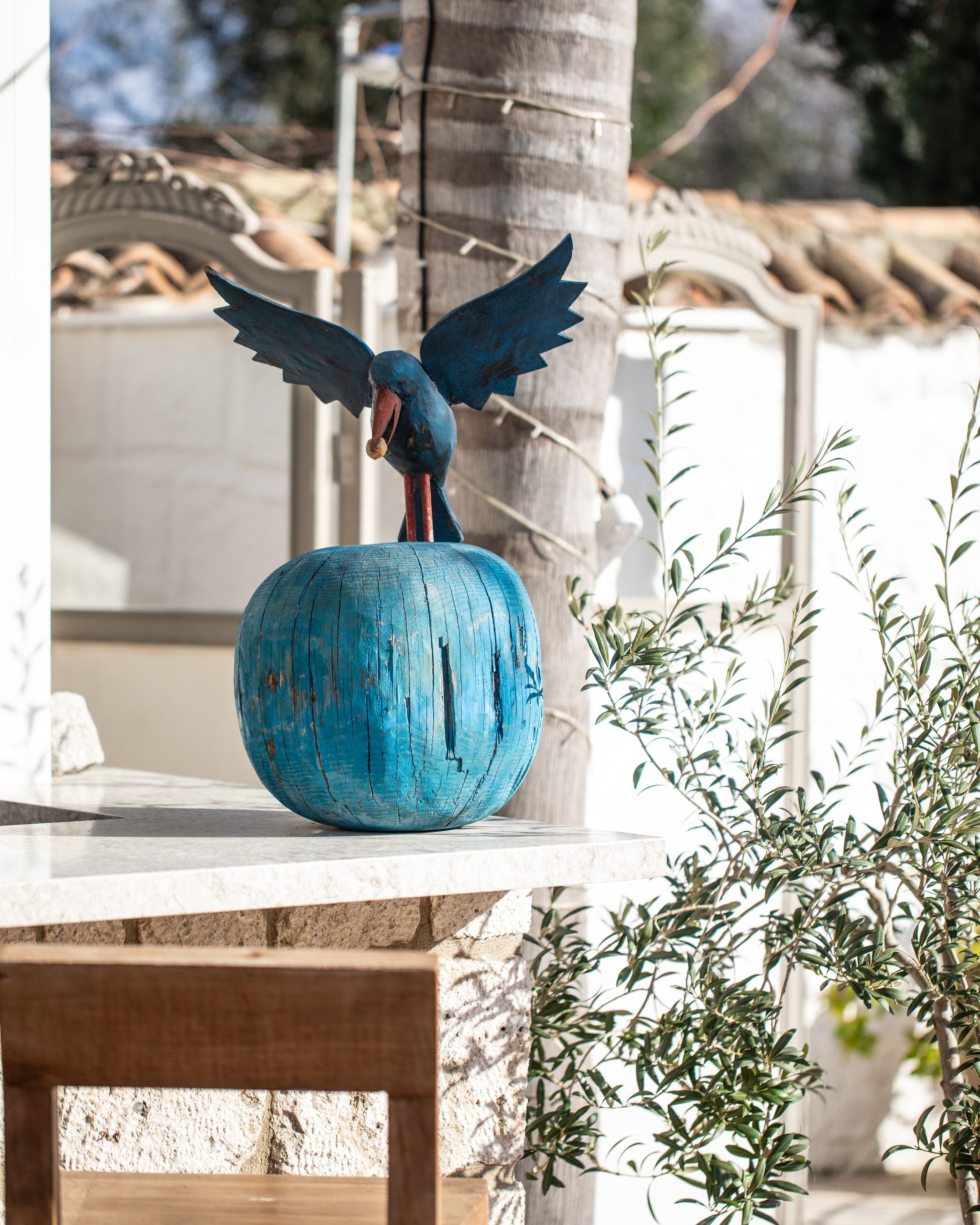 Una escultura de pájaro sobre una maceta azul.