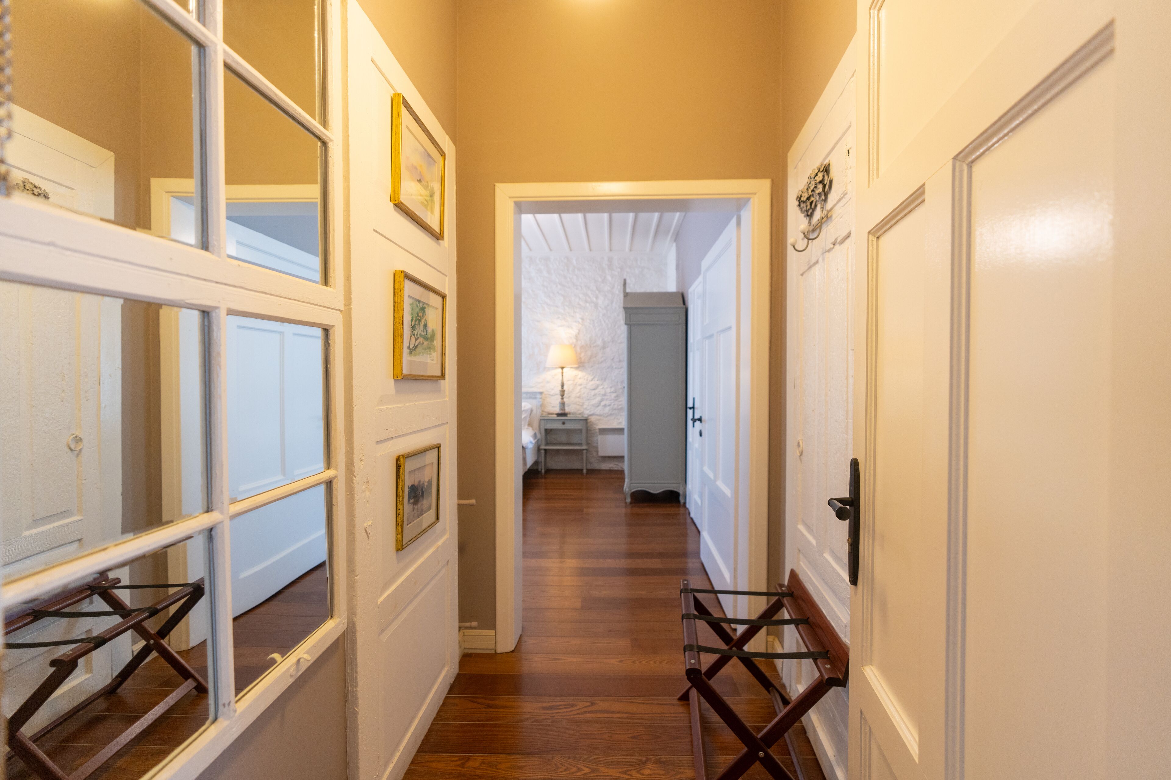 A hallway with wooden flooring, white walls, and doors leading to other rooms.