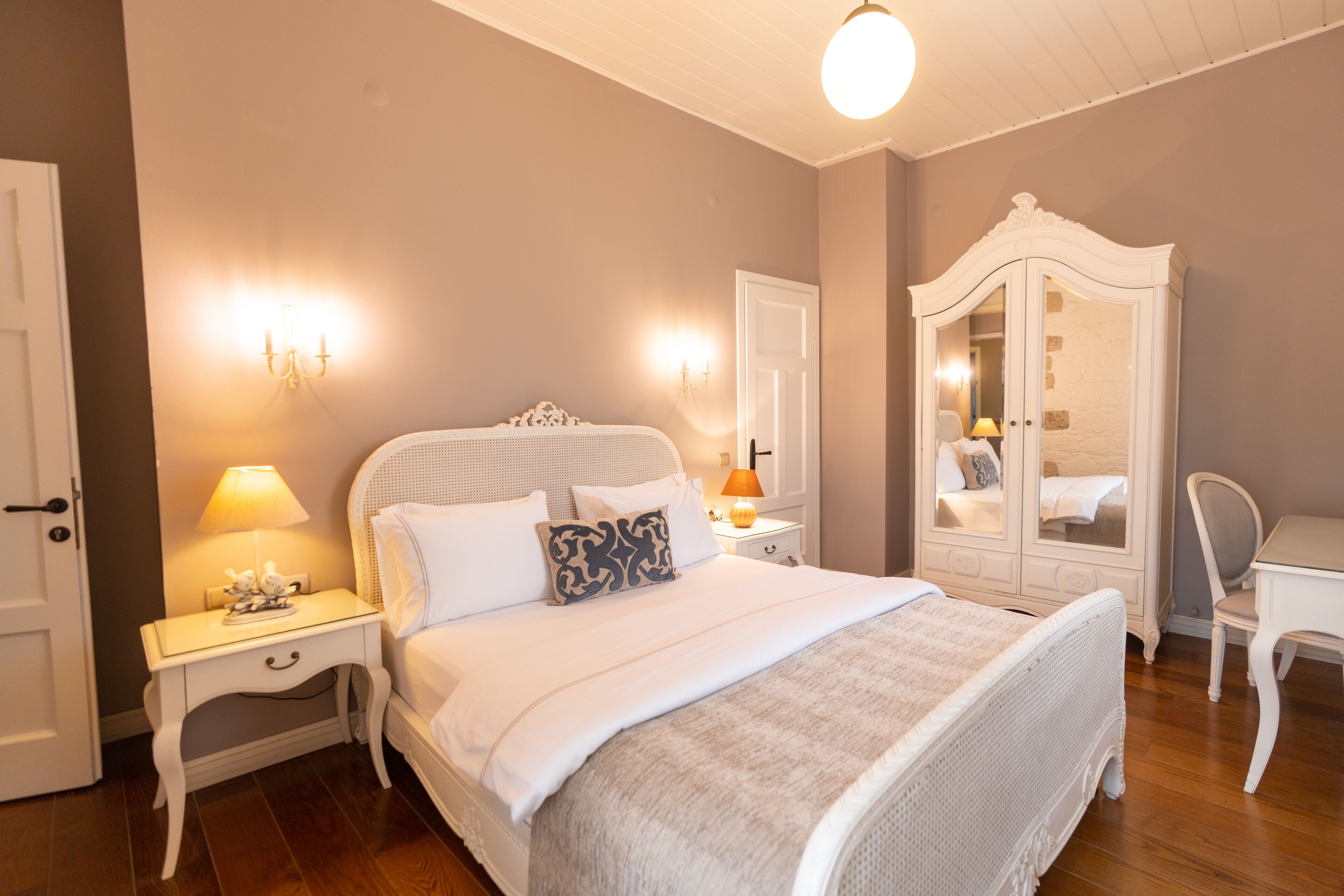 Een keurig opgemaakt slaapkamer met een bed, nachtkastjes, een kledingkast en een bureau.
