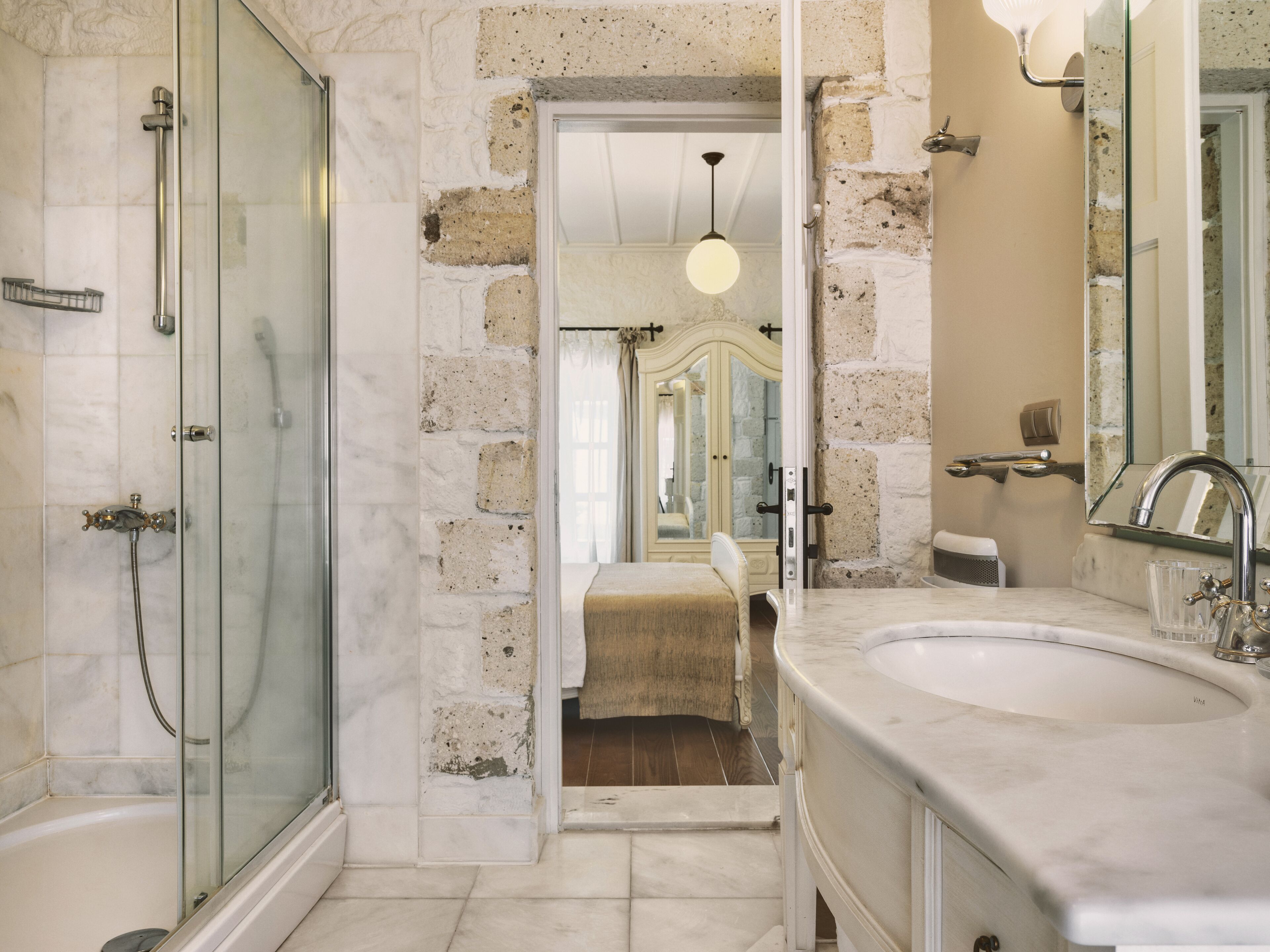 A bathroom with a glass-enclosed shower, a large marble sink, and a mirror.
