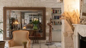 Une pièce chaleureuse avec un mur en pierre, un grand miroir, une cheminée et une bibliothèque.